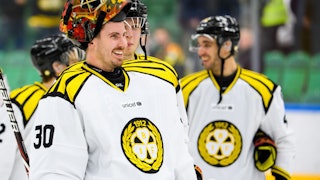 Brynäs målvakt Joacim Eriksson ler mot sina lagkamrater, med hjälmen uppdragen på huvudet.