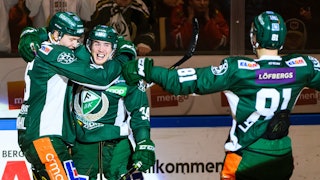 Tre glada spelare i Färjestads gröna matchdräkter jublar och kramar om varandra vid sargen