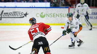 Örebros nummer 51 Kristian Näkyvä, med ryggen vänd mot kameran, i duell med en vitklädd Färjestadsspelare.